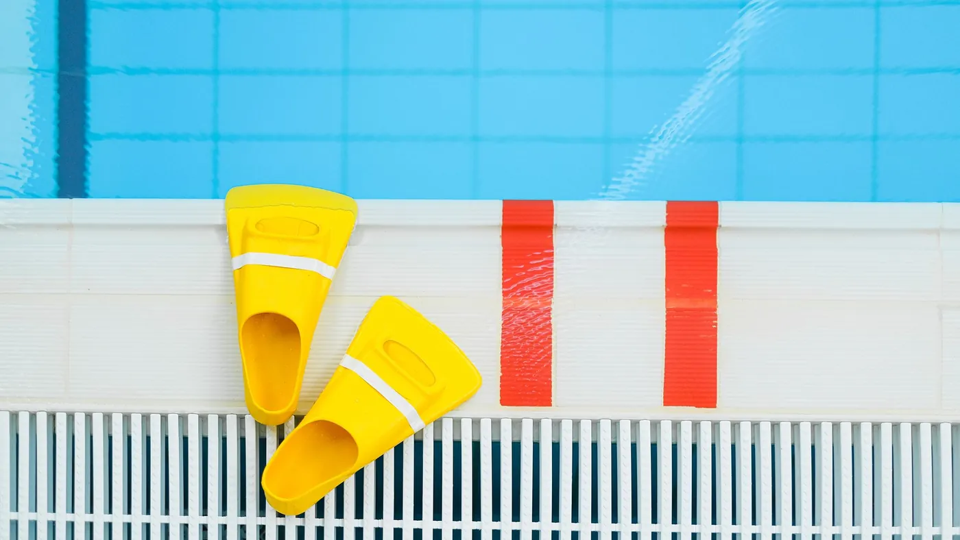 Schwimmflossen und Trainingsmaterial auf den Kacheln am Beckenrand