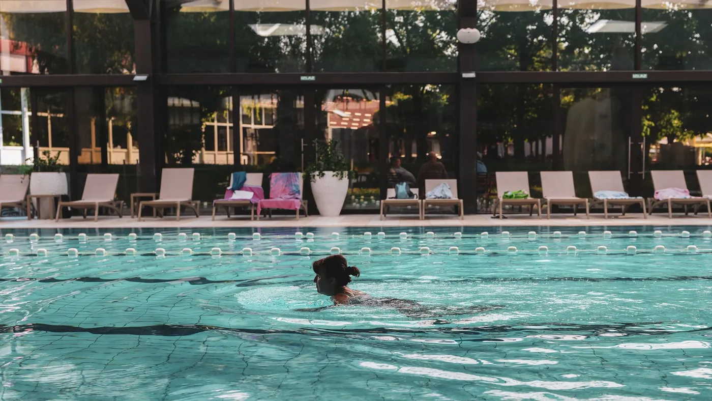 Freibadbecken mit Liegewiese und Schwimmerin am Vormittag