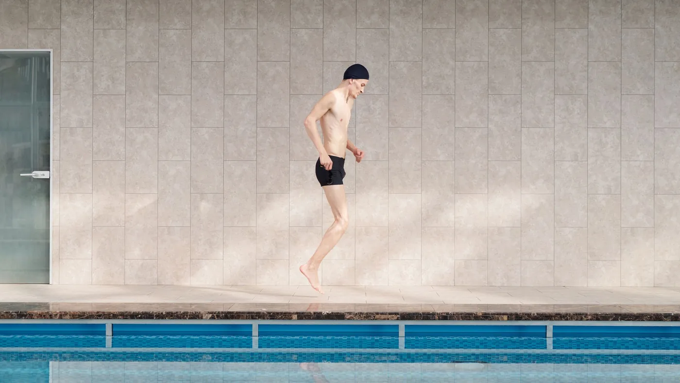 Person springt vom Beckenrand ins Wasser